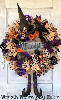 a wreath that says welcome with witch legs and witches hat on it, sitting in front of a door