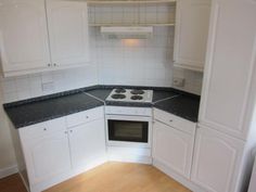 an empty kitchen with white cabinets and black counter tops