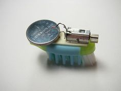 a small toothbrush with a tiny battery attached to it's back end on a white surface