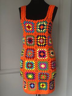 an orange crocheted dress is displayed on a mannequin