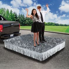 a man and woman standing on top of a table with silver tinsel in front of them