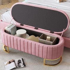 an open pink suitcase sitting on top of a bed next to a book and magazine