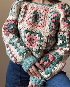 a woman is wearing a crocheted sweater with flowers on the sleeves and shoulders