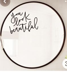 a round mirror with the words you got beautiful written in black ink next to a white brick wall