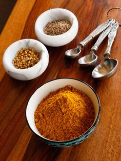 spices and measuring spoons sit on a table next to two bowls with food in them