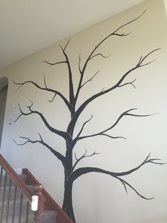 a tree painted on the side of a wall next to a banister stair case