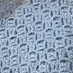 a crocheted blue blanket is laying on the floor