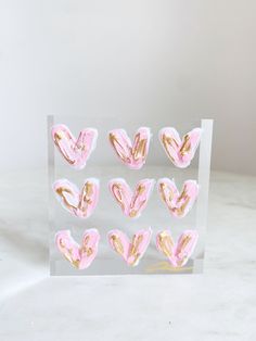 pink and gold hearts in a clear acrylic display case on a white surface