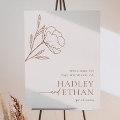 a welcome sign is shown on an easel next to some dried grass and flowers