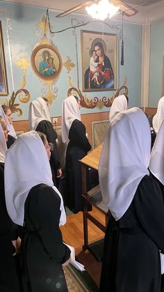 several women in nun dresses are standing at a table and some have headscarves on