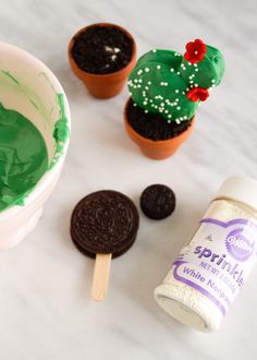 cupcakes with green frosting and chocolate cookies next to them on a table