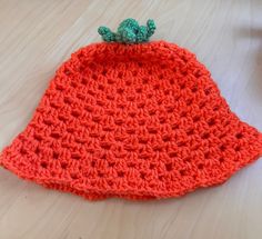 an orange crocheted hat sitting on top of a wooden table