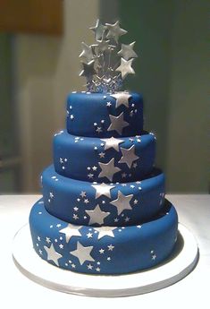 a three tiered blue cake with silver stars on it