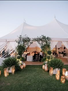 an outdoor tent with candles and greenery on the lawn