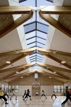 a group of people are dancing in a large room with high ceilings and wooden beams