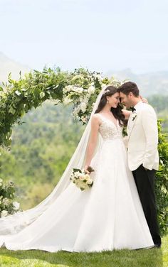 a bride and groom standing in front of an arch with greenery on the side