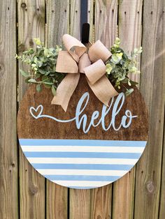 a wooden sign with the word hello painted on it and a bow hanging from it