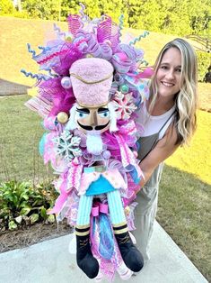 a woman standing next to a colorful doll