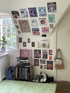 a room with a bed, laptop and various records on the wall next to a window