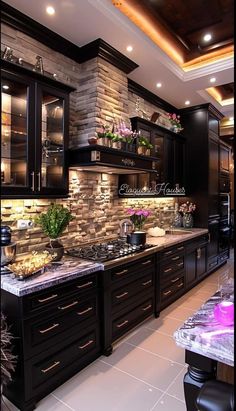 a large kitchen with black cabinets and marble counter tops on the walls is lit by recessed lights