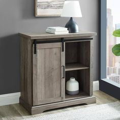 a wooden cabinet with two doors and a shelf on the side in front of a window