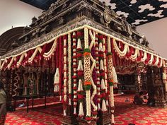 an elaborately decorated stage with flowers and garlands on the sides is displayed in a large room