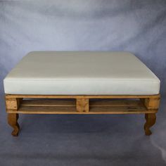 a white ottoman sitting on top of a wooden shelf next to a gray wall and floor