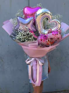 a woman holding a bunch of balloons and flowers