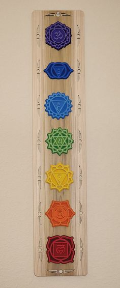 a wooden wall hanging with seven chakras in the shape of flowers on it