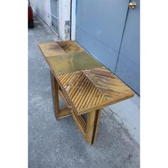 a wooden table sitting on the sidewalk next to a garage door and blue door behind it