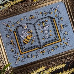 a cross - stitch book with bees and stars on it is surrounded by yellow flowers