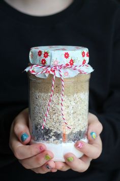 a woman holding a jar filled with sand and candy canes on top of it