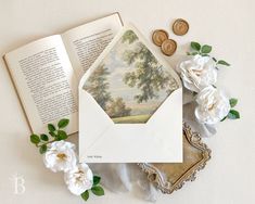 an open book and some white flowers on a table