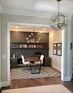 a room with a table, chairs and bookshelves on the wall in it