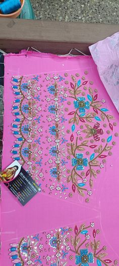 a pink table cloth with blue flowers and sequins on it, next to a pair of scissors