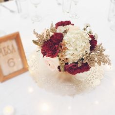 a bouquet of white and red flowers sitting on top of a table next to a framed sign