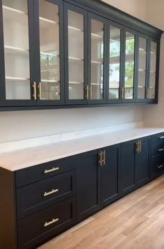 an empty kitchen with black cabinets and white counter tops in the middle of the room