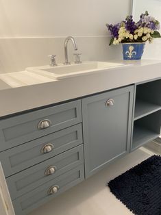 a white sink sitting under a bathroom mirror next to a blue rug on the floor