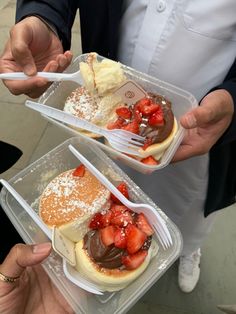 two people holding plastic containers filled with desserts and strawberries on top of each other