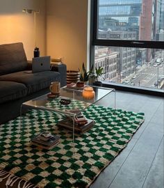 a living room with a couch, coffee table and large window looking out on the city