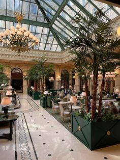 the inside of a hotel lobby with palm trees and chandeliers hanging from the ceiling