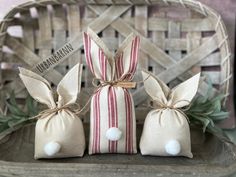 two small bags with bunny ears tied to them, sitting on a table in front of a wicker basket