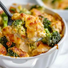 a spoon full of broccoli casserole being lifted from a white dish