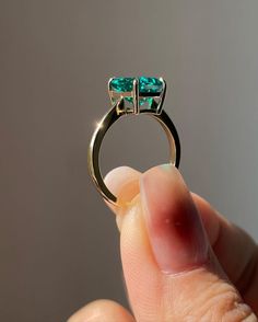 someone is holding an emerald ring in their hand