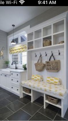 a kitchen with white cabinets and yellow towels on the counter top, along with baskets hanging from hooks