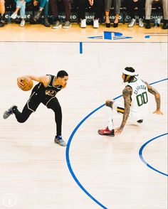 two men playing basketball on a court with people watching