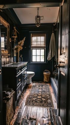 a bathroom with wooden floors and black walls, along with a rug on the floor