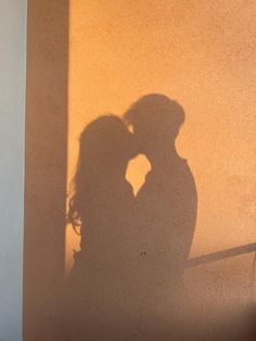 the shadow of two people standing next to each other on a wall with their arms around each other