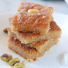 three pieces of cake sitting on top of a white plate next to pistachios