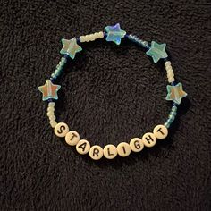 a beaded bracelet with name and star charms on it sitting on a black surface